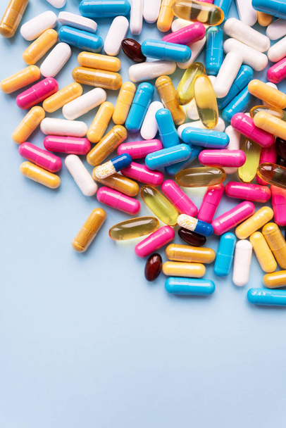 Beaucoup de pilules et capsules colorées pour différents symptômes sur un fond bleu. Santé et médecine concept - Photo, image