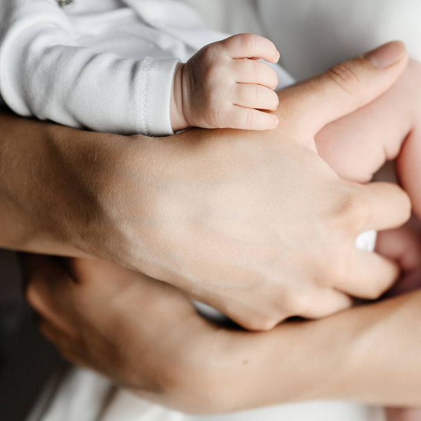 生まれたばかりの赤ん坊の小さな手,母親は赤ちゃんをサポートしています. - 写真・画像