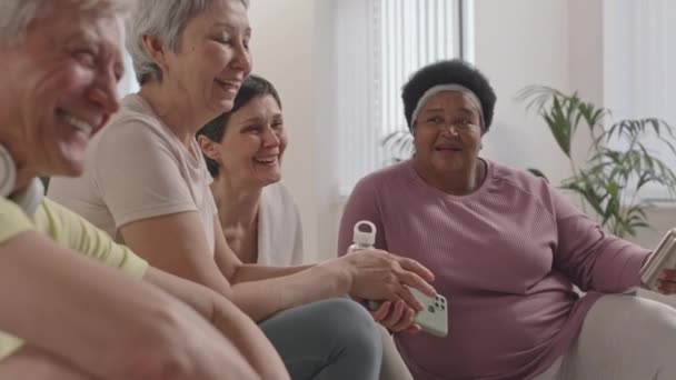 Стійка фокус знімок веселих старших жінок і чоловік обговорює, сміється і посміхається під час відпочинку після групової фітнес-тренувань - Кадри, відео