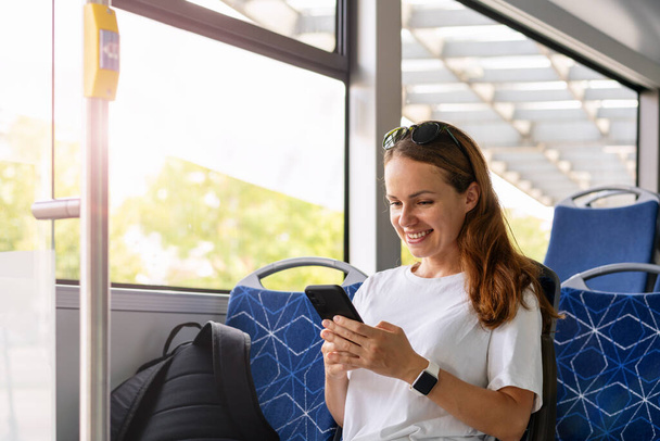 Lebensstil im öffentlichen Nahverkehr. Frau benutzte ihr Smartphone während der Fahrt im Shuttlebus. - Foto, Bild