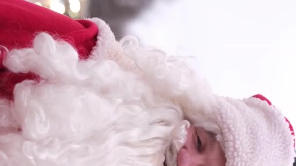 Santa Claus s plnovousem a širokým úsměvem s palcem nahoru. Zavřít. Svislé video. - Záběry, video