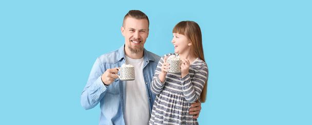 青い背景にホットココアのカップと幸せな娘と父親 - 写真・画像
