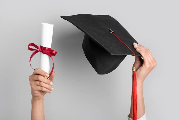 Femme avec chapeau de graduation et diplôme sur fond gris - Photo, image