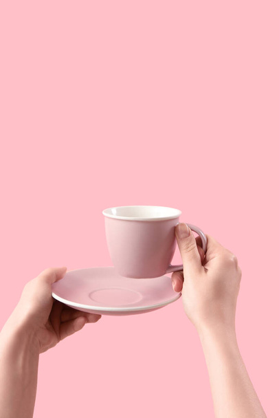 Női kéz tartó csésze és csészealj rózsaszín háttér - Fotó, kép