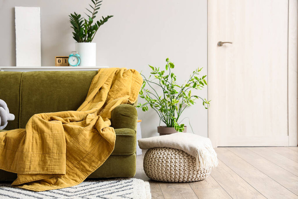 Canapé et pouf vert avec couvertures douces à l'intérieur du salon lumineux - Photo, image