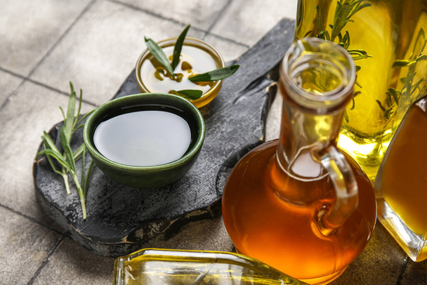 Bowls and jug of fresh olive oil on grey tile background - Photo, Image