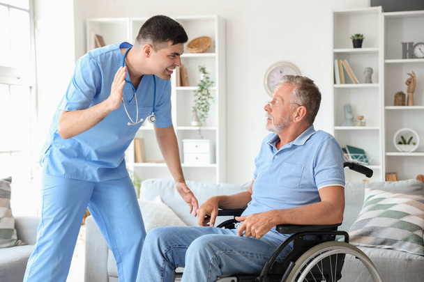Uomo anziano in sedia a rotelle spaventato di infermiera arrabbiata a casa - Foto, immagini