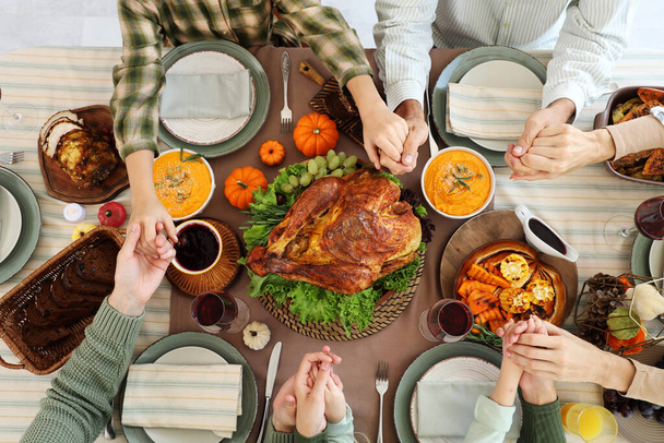 Gelukkig gezin biddend voor het diner aan feestelijke tafel op Thanksgiving Day, bovenaanzicht - Foto, afbeelding