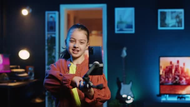 Happy child taking part in viral dance craze after seeing favorite celebrities doing it, filming video with smartphone attached to selfie stick, doing trendy challenge for online fans - Footage, Video