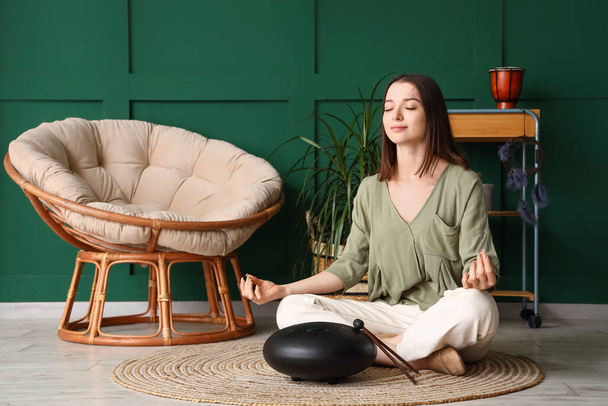 Młoda kobieta z glukofonią medytująca w domu - Zdjęcie, obraz