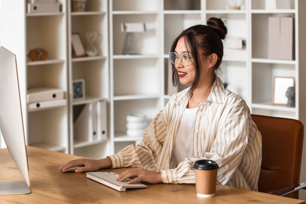 Молода азіатська бізнес-леді працює з комп'ютером за столом в офісі - Фото, зображення