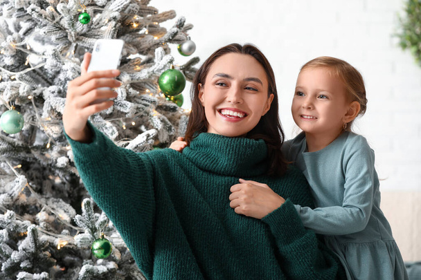 Gelukkig jong moeder en haar dochtertje nemen selfie thuis op kerstavond - Foto, afbeelding