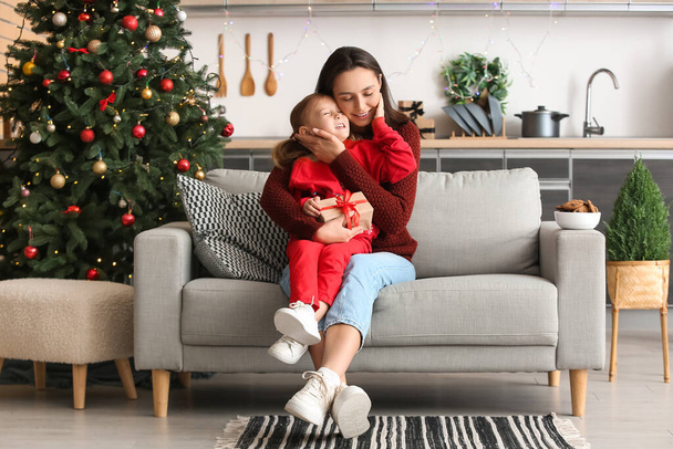 Young mother and her little daughter with Christmas gift at home - Photo, Image