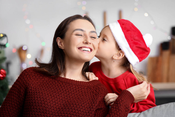 Glückliche Mutter und ihre kleine Tochter mit Weihnachtsmütze zu Hause an Heiligabend - Foto, Bild