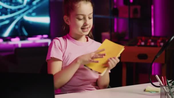 Kleines Mädchen präsentiert ihr neues Lieblingsbuch, nachdem sie es als Hausaufgabe von der Schule erhalten hat. Kid Content Creator Shooting Kinderliteratur Review-Video für Social Media-Kanal - Filmmaterial, Video