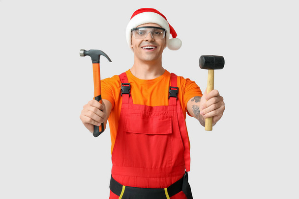 Красивый мужчина строитель в Санта шляпе с молотками на белом фоне - Фото, изображение