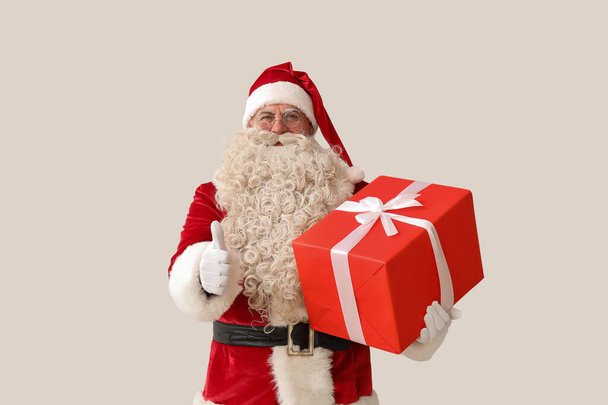 Weihnachtsmann mit Weihnachtsgeschenk mit Daumen nach oben auf weißem Hintergrund - Foto, Bild