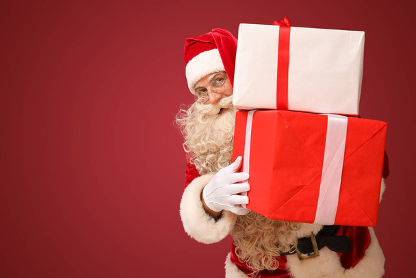 Santa Claus with Christmas gifts on red background - Photo, Image
