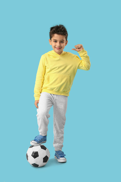 Симпатичный маленький мальчик с футбольным мячом на синем фоне - Фото, изображение