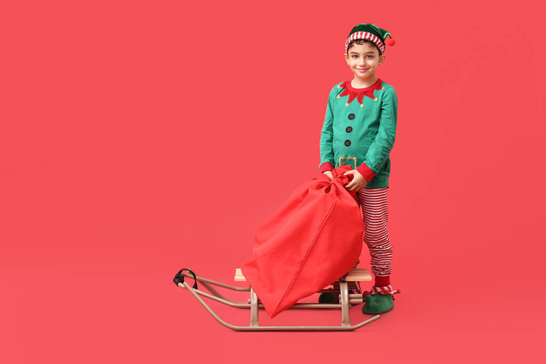 Aranyos kis manó szánkó és táska ajándékok piros háttér - Fotó, kép