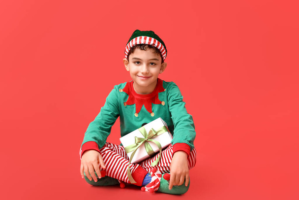 Cute little elf z prezentem świątecznym na czerwonym tle - Zdjęcie, obraz