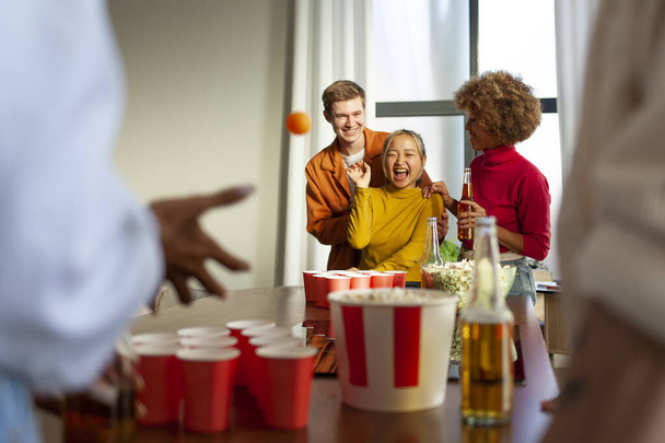 багаторасова група молодих друзів, які грають пивний понг на вечірці, п'ють пиво і розважаються вдома, студенти п'ють алкоголь і святкують перемогу - Фото, зображення