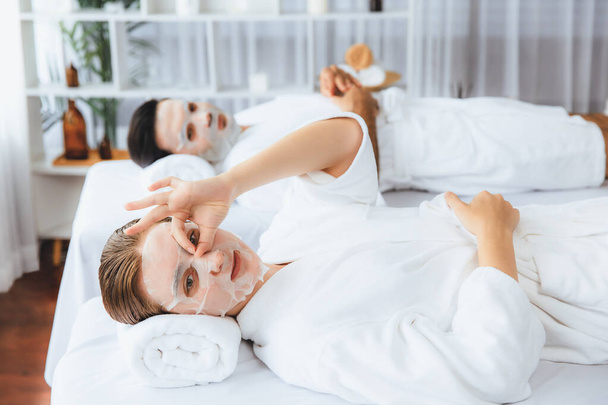 Spokojna, nowoczesna atmosfera światła dziennego w salonie spa, para klientów odmładza się maską do pielęgnacji twarzy. Zabieg pielęgnacji twarzy i kosmetologii twarzy. Cichy zapach - Zdjęcie, obraz