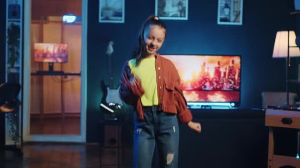Happy kid doing professional dance moves for online streaming service, doing viral challenge. Cheerful girl recording video for her internet viewership in dimly lit personal studio - Footage, Video