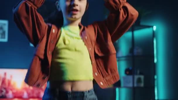 Klein meisje neemt deel aan virale dans rage na het zien van favoriete beroemdheden doen. Een klein kind danst voor social media invloed, doet trendy uitdaging. voor online fans in slecht verlichte thuisstudio - Video