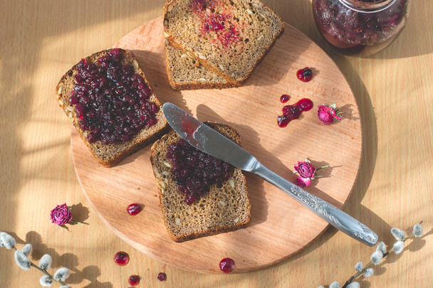 Φρέσκα σπιτικά υγιή ψωμί ψημένο με φραγκοστάφυλο μαρμελάδα - σπιτικές μαρμελάδες με φρέσκα βιολογικά φρούτα από τον κήπο. Στο ρουστίκ διακόσμηση, γλυκά κουταλιού σε ξύλινο τραπέζι φόντο. Τέλειο γλυκό πρωινό - Φωτογραφία, εικόνα