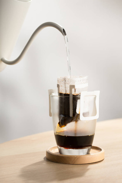 A forró vizet a pörkölt és őrölt kávéra öntjük, használatra kész szűrőpapírba.. - Fotó, kép