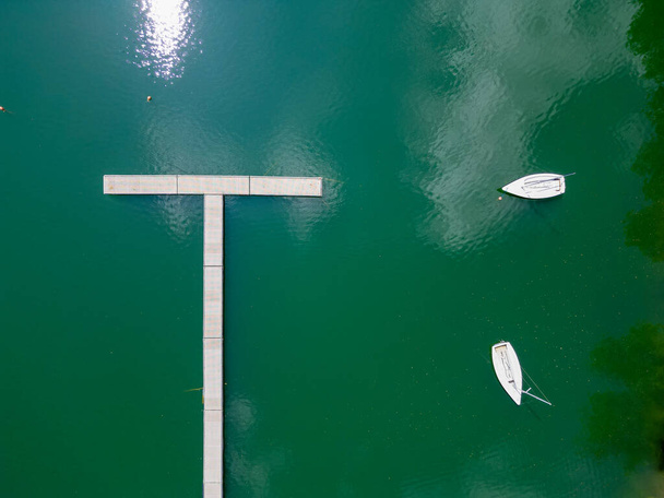 Hangend in de lucht biedt de camera een uniek uitzicht over een bruisende zeilclub. De top-down uitzicht legt een perfect patroon van aangemeerde zeilboten genesteld in de baai van de zee. De kalme - Foto, afbeelding