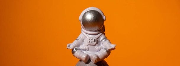 Plastic toy astronaut on colorful orange background Copy space. Concept of out of earth travel, private spaceman commercial flights. Space missions and Sustainability - Photo, Image