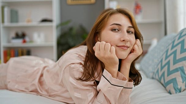 Mladá žena ležící na posteli s vážnou tváří v ložnici - Fotografie, Obrázek
