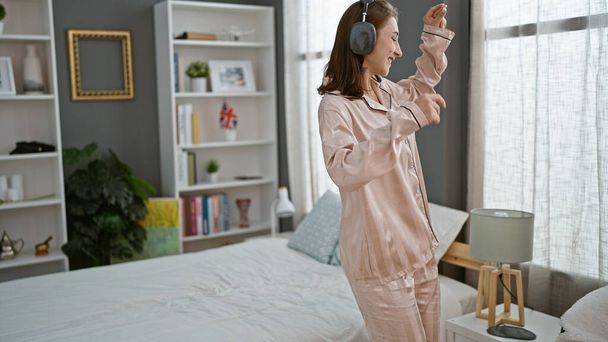 Genç kadın yatak odasında müzik dinliyor. - Fotoğraf, Görsel
