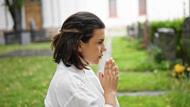 Piękna młoda Latynoska modląca się i opłakująca nagrobek na cmentarzu - Zdjęcie, obraz