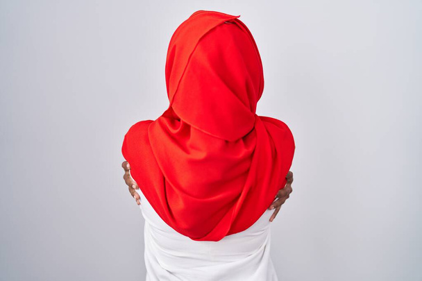 Mujer árabe joven vistiendo bufanda islámica tradicional hijab abrazándose feliz y positivo desde atrás. amor propio y cuidado personal  - Foto, Imagen