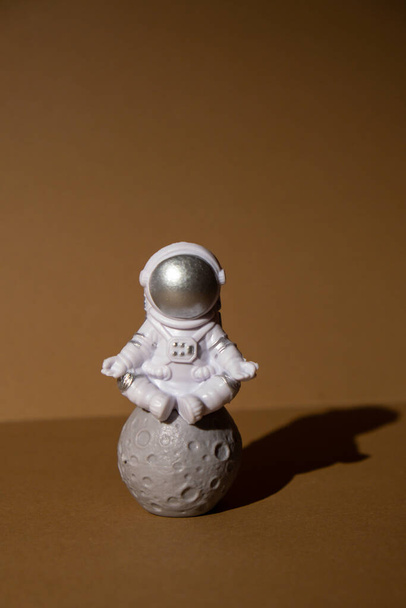 Plastic toy figure astronaut on beige neutral background Copy space. Concept of out of earth travel, private spaceman commercial flights. Space missions and Sustainability - Fotó, kép