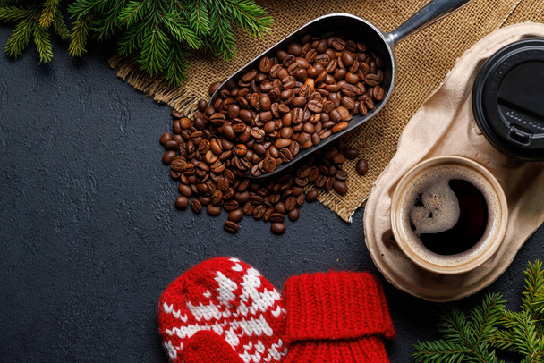 Кофейная чашка, жареные кофейные зёрна и елки в уютной обстановке. Рождественская открытка с копировальным местом - Фото, изображение