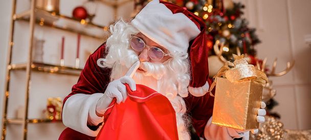 Santa Claus con bolsa roja llena de regalos para los niños en casa. Año Nuevo y Feliz Navidad concepto  - Foto, Imagen