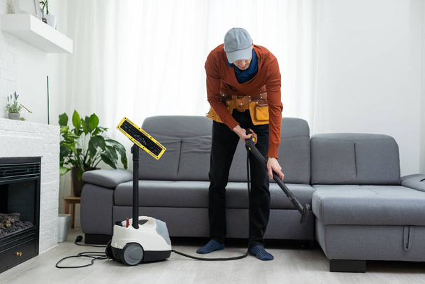 Čistírna muž zaměstnanec odstraňování nečistot z nábytku v bytě, detailní, vysavač čistý gauč s profesionálním vybavením - Fotografie, Obrázek