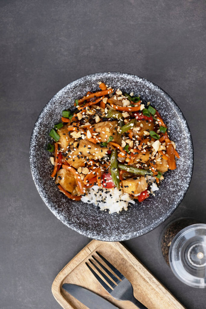 Tigela com arroz saboroso, carne e legumes no fundo escuro vista superior, flat lay. - Foto, Imagem
