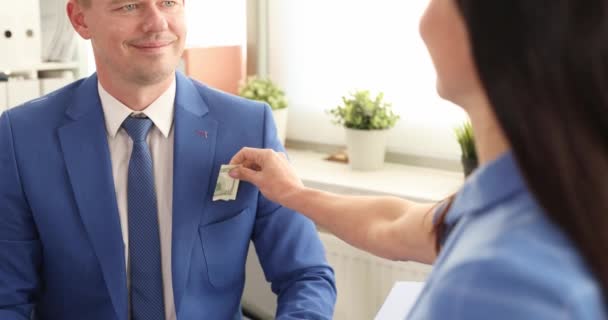 Businesswoman puts money in pocket of smiling businessman and shakes hands. Responsibility for giving and receiving bribes concept - Footage, Video