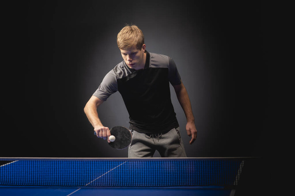 Portret van een jonge man die tennis speelt op een zwarte achtergrond - Foto, afbeelding