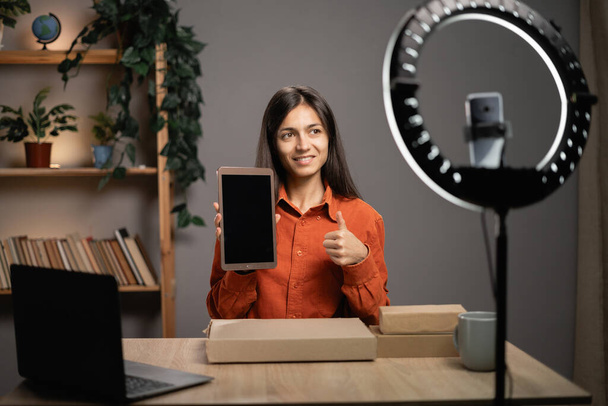 Il blogger registra una recensione video di un tablet moderno su una fotocamera di uno smartphone in uno studio domestico, influenzatore dei social media che pubblicizza un prodotto tecnologico. Copia spazio - Foto, immagini