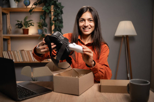 Vídeo de desempacotar óculos de realidade virtual modernos, uma blogueira feminina gravando uma revisão de produto na câmera para seus assinantes. Espaço de cópia - Foto, Imagem