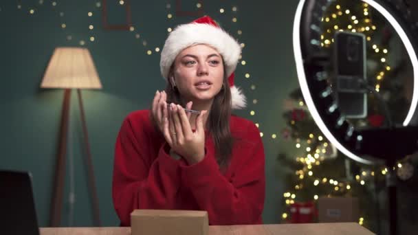 Junge Frau mit Weihnachtsmütze bei der Aufnahme eines Unboxing-Videos in ihrem Heimatstudio. Kopierraum - Filmmaterial, Video