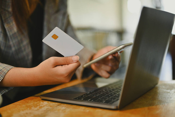 Νεαρή επιχειρηματίας που κατέχει πιστωτική κάρτα χρησιμοποιώντας κινητό τηλέφωνο κάνει online τραπεζική συναλλαγή ή ψώνια στο ηλεκτρονικό κατάστημα. - Φωτογραφία, εικόνα