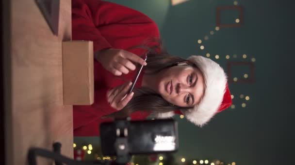 Γυναίκα blogger κοινωνική επιρροή των μέσων μαζικής ενημέρωσης καταγραφή βίντεο αναθεώρηση της unboxing gadget στο σπίτι. Ζωντανά μέσα κοινωνικής δικτύωσης, Πρωτοχρονιά, Χριστουγεννιάτικη ιδέα. κατακόρυφο βίντεο - Πλάνα, βίντεο