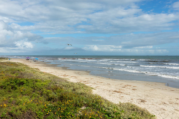 Az emberek élvezik a gyönyörű homokos strandot a Mexikói-öbölben Galveston szigetén, drámai gyönyörű égbolttal Texasban, USA-ban.. - Fotó, kép
